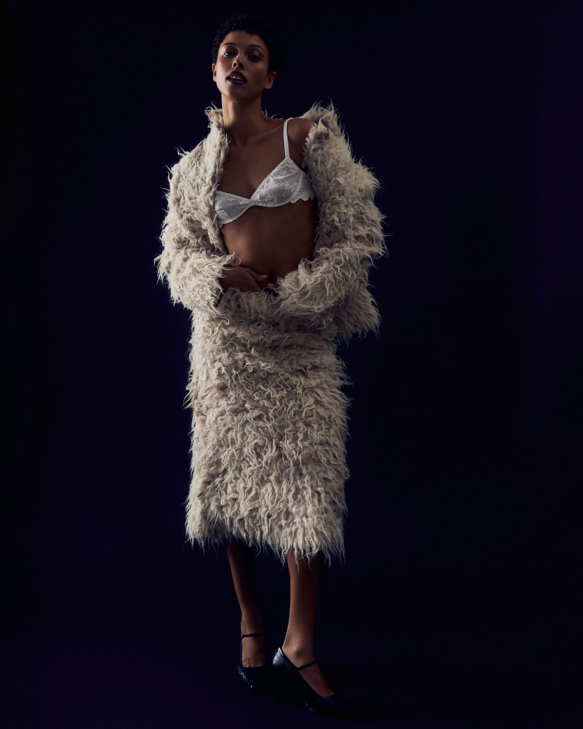 Faith Love Hope editorial: shaggy cream coat and skirt against a dark backdrop