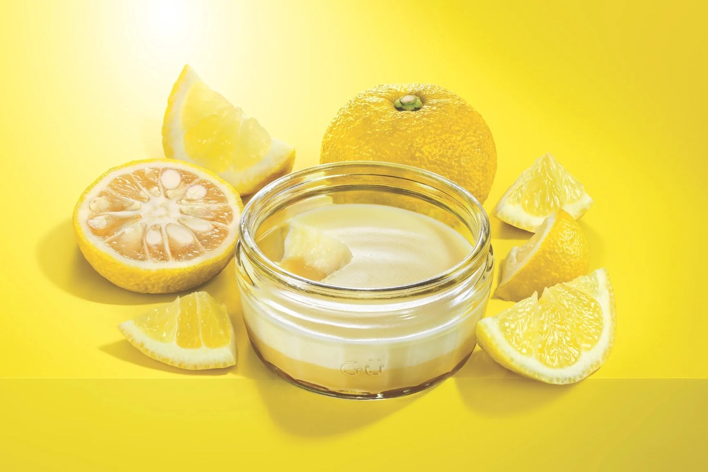 Gü yuzu dessert in a glass ramekin surrounded by cut yuzu